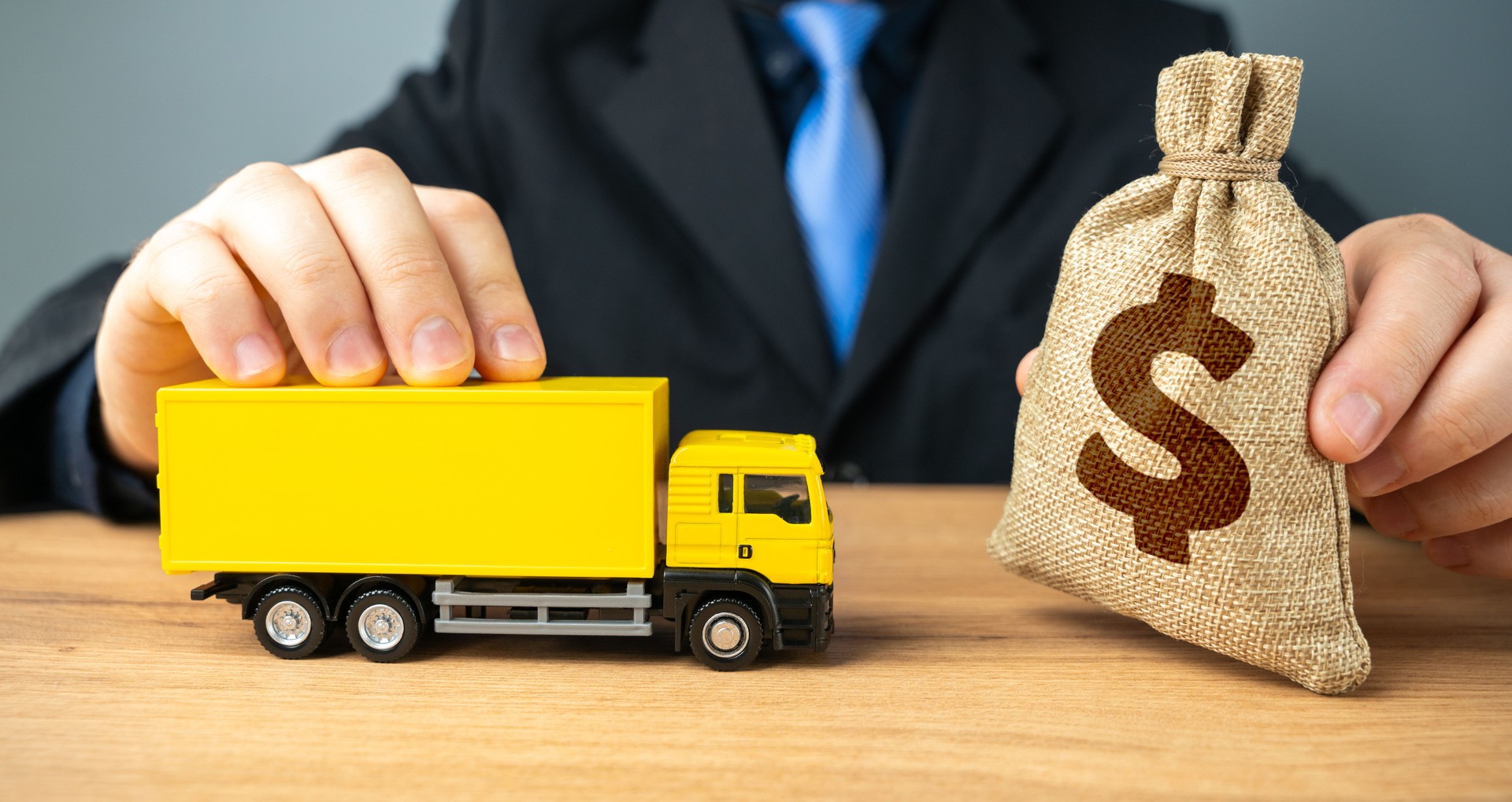 Businessman holding dollar money bag and delivery truck. Investments in transport infrastructure. Purchase of new trucks and rolling stock. Profit from the transport company, industry.
